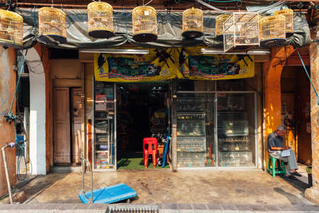 Kuala Lumpur, Malaysia - March 17, 2016:  Birds vendor  sitting before his shop in Chinatown, Kuala Lumpur, Malaysia on March 17, 2016.のeditorial素材