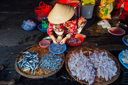 Nha Trang, Vietnam - July 14, 2016: Vietnamese woman in conical hat sells fish at the morning market in Nha Trang, Vietnam on July 14, 2016.のeditorial素材