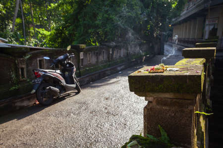 Burning offerings on the old mossy bridge in the morning hour, Ubud, Bali, Indonesia.