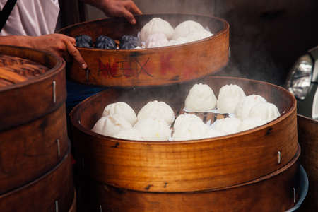 Kuala Lumpur, Malaysia - March 17, 2016:  Young man cooking chinese traditional steamed buns at the street food stall in Chinatown, Kuala Lumpur, Malaysia on March 17, 2016.のeditorial素材
