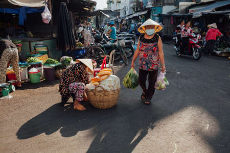 Nha Trang, Vietnam - July 14, 2016: Vietnamese woman in conical hat walks at the morning market in Nha Trang, Vietnam on July 14, 2016.のeditorial素材