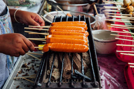 A street vendor makes grilled Thai sausages on skewers at the Warorot Market, Chiang Mai, Thailand.の写真素材