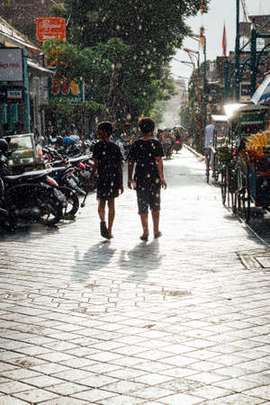 Ubud, Indonesia - March 08, 2016: Kids walk under the sun shower on the street of Ubud, Bali, Indonesia on March 08, 2016のeditorial素材