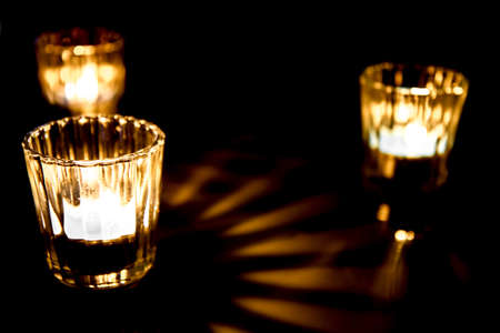 Three small burning candles in glass cups on the tableの写真素材