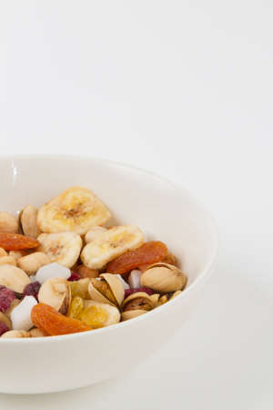 Bowl of mixed healthy snacks on a white background with copy spaceの写真素材