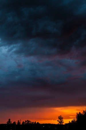 poster cloudscape of setting sun and dark stormy clouds with vivid colors.の写真素材