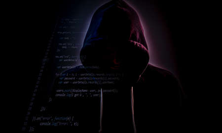 Malicious figure in hood lurking in the dark with some code layerの写真素材