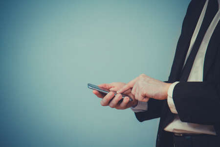 business man in a suit using his smart phone with blue backgroundの写真素材