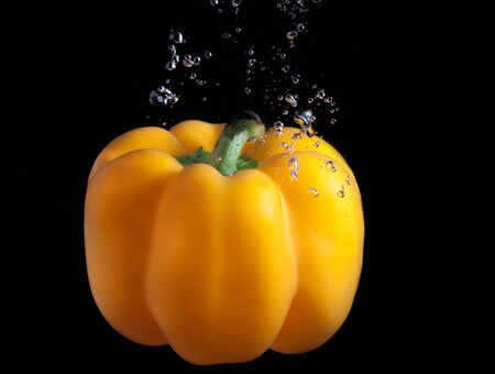Yellow paprika splash in water on black background. の写真素材