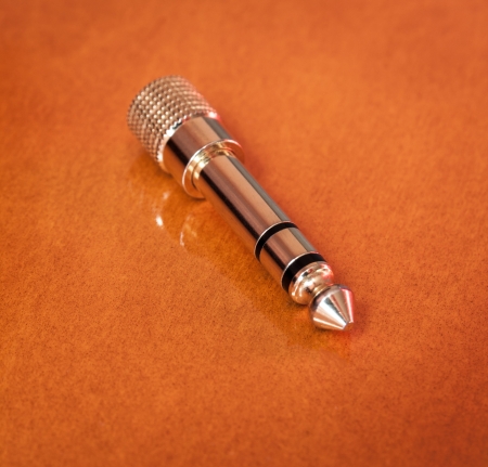 	Golden headphone jack plug on a reflective wooden background.の写真素材