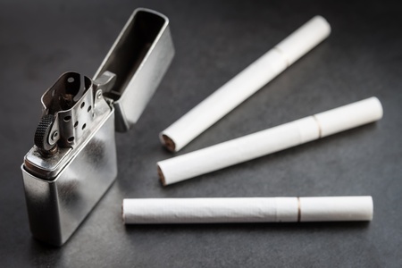 Open metal lighter and three cigarettes on dark backgroundの写真素材