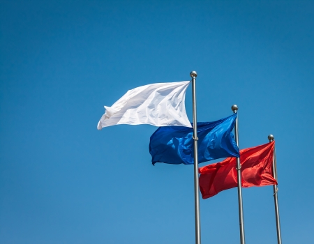 White, blue and red flags against blue sky の写真素材