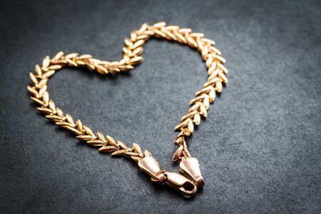    Heart shaped gold chain on dark background  Macro shot with shallow depth of field  Selective focus の写真素材