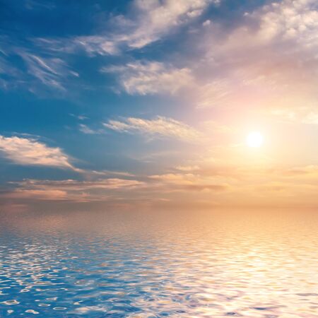 Sunset with clouds reflected in water の写真素材