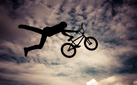   Silhouette of a man doing an jump with a bmx bike  Color toned image の写真素材
