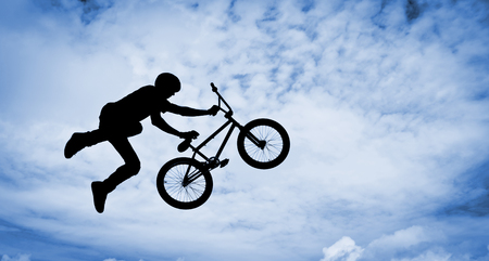   Silhouette of a man doing an jump with a bmx bike  Color toned image の写真素材