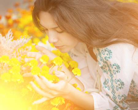   Young girl smelling yellow flowers with the sunshine  の写真素材