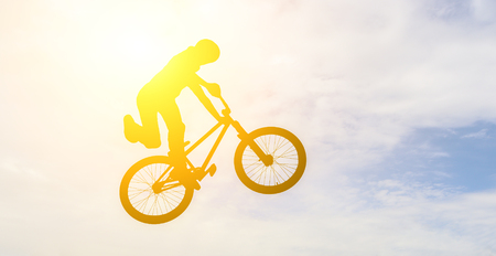  Man doing an jump with a bmx bike against sunshine sky  の写真素材