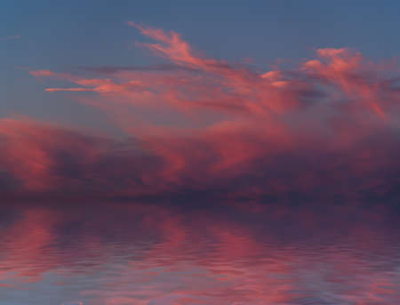 Dramatic sunset with clouds reflected in water.の写真素材