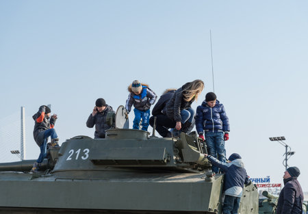 VLADIVOSTOK, RUSSIA - FEBRUARY 23, 2015: Children play on modern russian armored vehicle during festivities devoted to Defender of the Fatherland Day.のeditorial素材