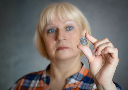 Woman holding coin on grey background. Selective focus.の写真素材
