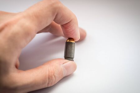Bullet in fingers on white background. Selective focus on bullet.の写真素材