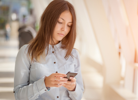 Young businesswoman inside office with smartphone.の写真素材
