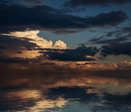 Dramatic sunset with clouds reflected in water.の写真素材