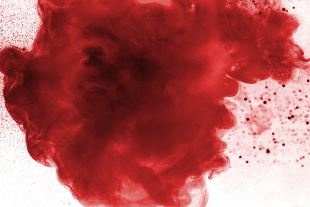 Red watercolor in water with small pieces of paint.の写真素材
