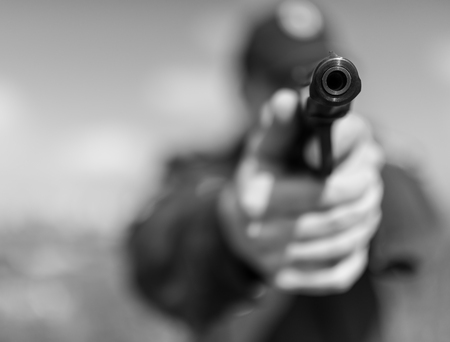 Detail of a police officer holding gun. Selective focus with shallow depth of field. Black and white...