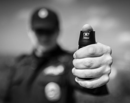 Detail of a police officer holding pepper spray. Selective focus with shallow depth of field. Black and white toning.の写真素材