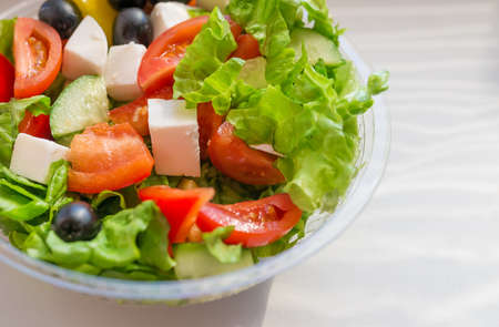 Greek salad with vegetables, cheese and olives in plastic container. Selective focus.の写真素材