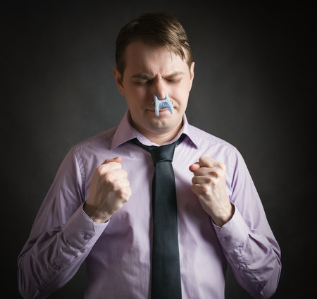 Portrait of young businessman man with clothespin on his nose - bad smell concept photography.の写真素材