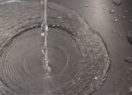 Water flowing down the hole in a kitchen sink. Selective focus.の写真素材