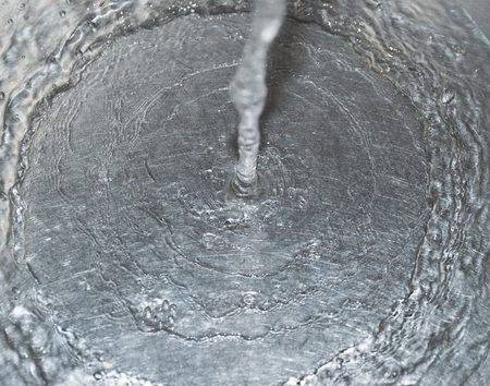 Water flowing down the hole in a kitchen sink. Selective focus.の写真素材