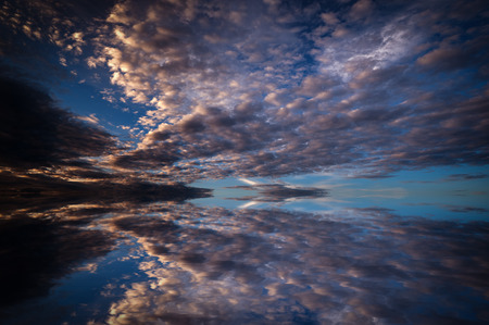 Dramatic sunset with clouds reflected in water.