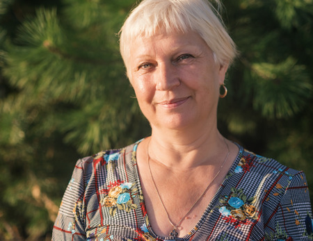 Portrait of beautiful aged woman in the park at sunset.