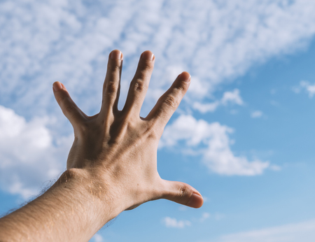 Hand of a man reaching to towards sky. Color toned image. Selective focus.の写真素材