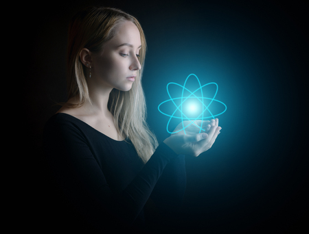 Young woman with glowing atom model - science concept.の写真素材