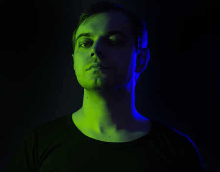 Portrait of a man with colored light and dark background.