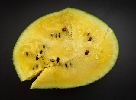 Fresh yellow watermelon slice on dark background.の写真素材