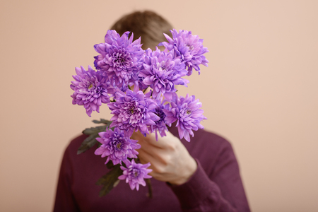 Young man with purple flowers in his hand.の写真素材