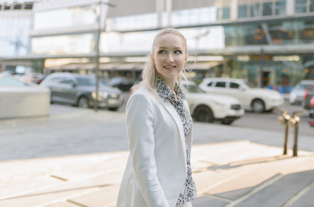 Outdoors portrait of young woman in white jacket.の写真素材