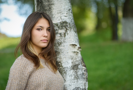 Portrait of young woman leaned to the birch tree.の写真素材