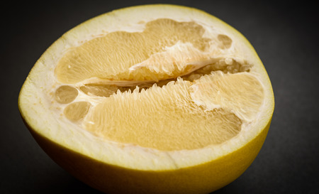 Half of pomelo fruit on dark background.
