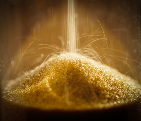 Sand grains in the hourglass. Shallow depth of field.