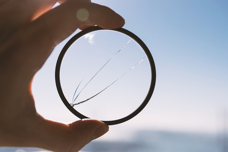 Hand hold broken photo-filter over blue sky background.の写真素材
