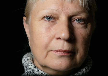 Middle aged woman portrait in sweater on dark background.の写真素材