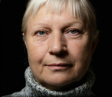 Middle aged woman portrait in sweater on dark background.の写真素材