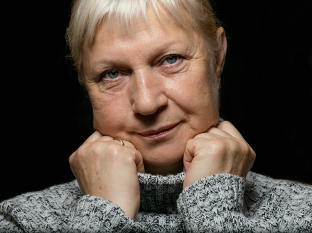 Middle aged woman portrait in sweater on dark background.